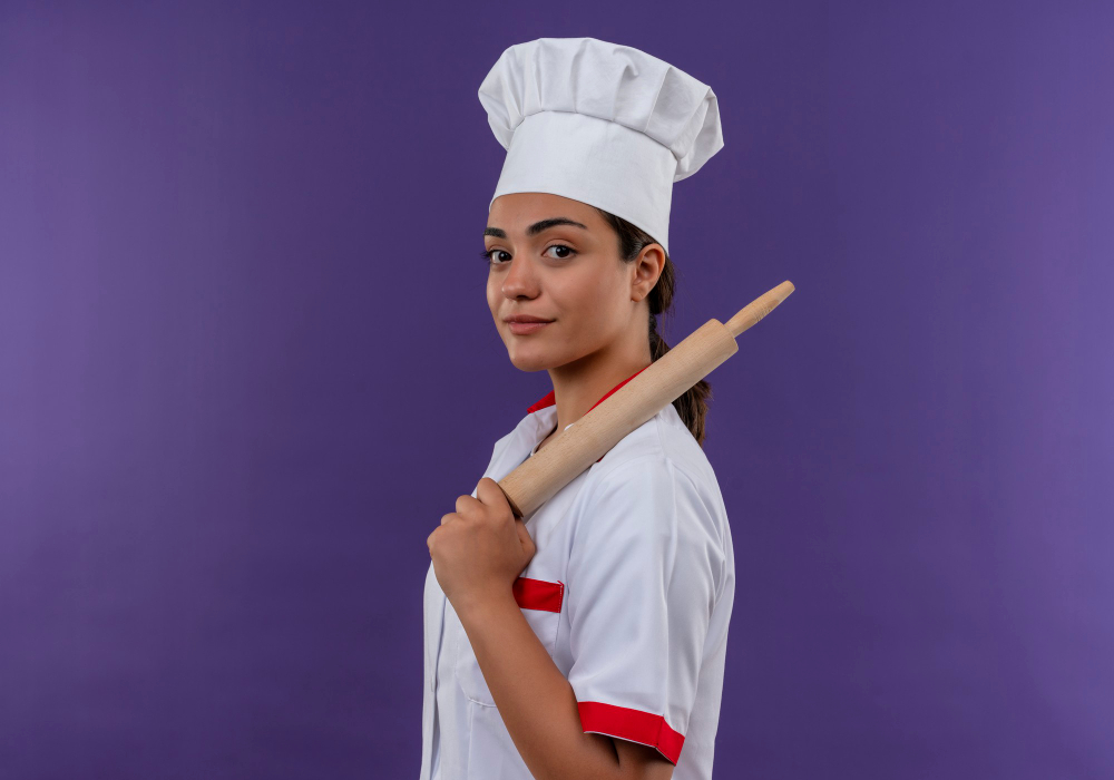 young-confident-caucasian-cook-girl-chef-uniform-stands-sideways-holds-rolling-pin-isolated-violet-wall-with-copy-space